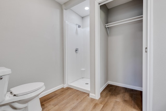 bathroom featuring toilet, wood-type flooring, and walk in shower