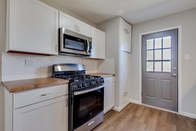 kitchen with backsplash, light hardwood / wood-style floors, stainless steel appliances, white cabinets, and butcher block countertops