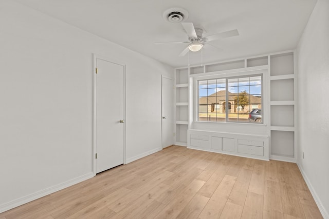 empty room with ceiling fan, light hardwood / wood-style flooring, and built in features