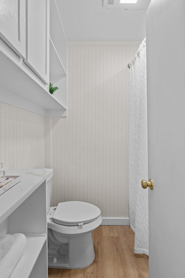 bathroom with toilet, wood walls, and wood-type flooring