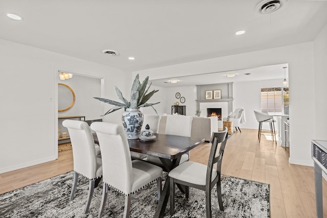 dining space with a fireplace and light hardwood / wood-style flooring