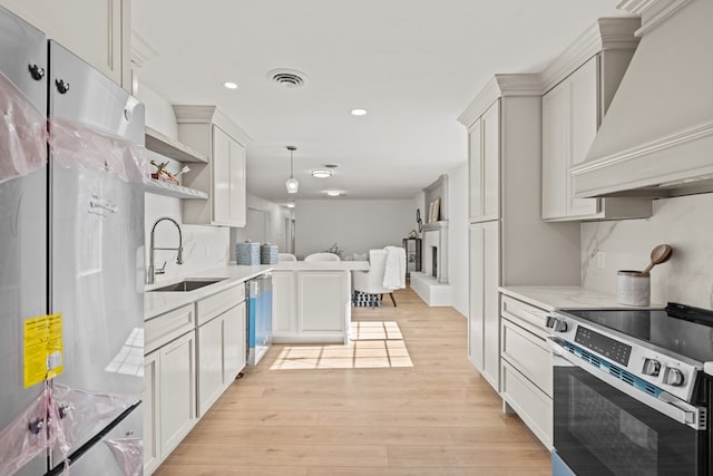 kitchen featuring custom exhaust hood, stainless steel appliances, pendant lighting, white cabinets, and sink