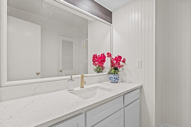 bathroom featuring ornamental molding, wooden walls, and vanity