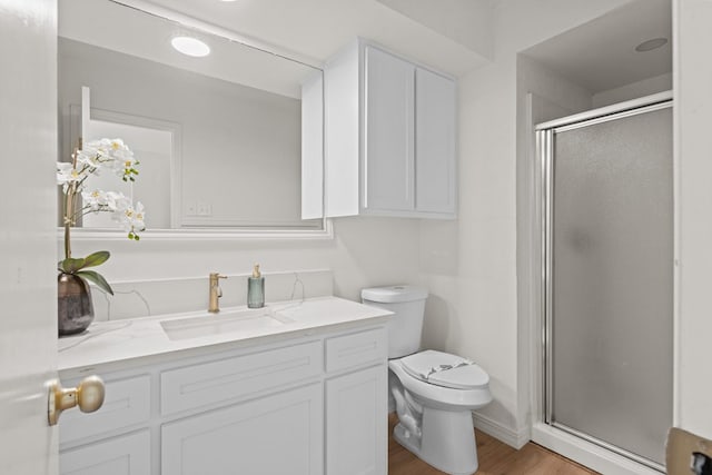 bathroom featuring wood-type flooring, vanity, a shower with shower door, and toilet