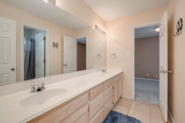 1608 Castleford Rd, Midland, TX 79705 - bathroom featuring double vanity, a textured ceiling, a sink, tile patterned floors, and baseboards