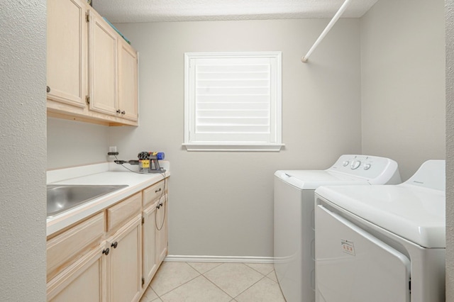 1608 Castleford Rd, Midland, TX 79705 - clothes washing area featuring washing machine and clothes dryer, cabinet space, a sink, baseboards, and light tile patterned flooring