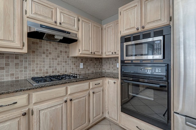 1608 Castleford Rd, Midland, TX 79705 - kitchen with appliances with stainless steel finishes, tasteful backsplash, light tile patterned floors, dark stone countertops, and under cabinet range hood