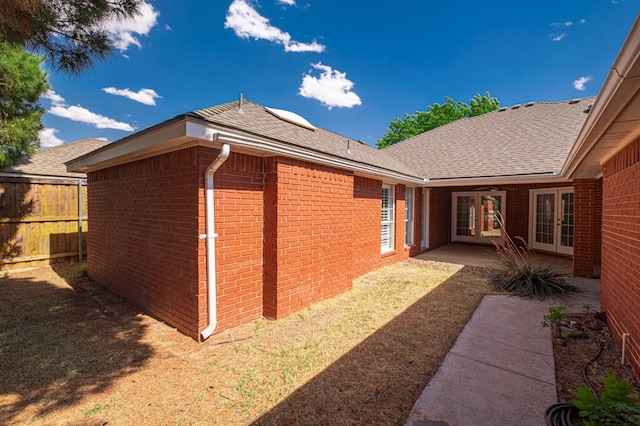1608 Castleford Rd, Midland, TX 79705 - view of property exterior with brick siding, roof with shingles, fence, and french doors