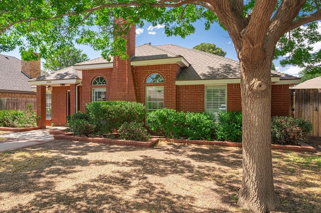 1608 Castleford Rd, Midland, TX 79705 - view of front of property with brick siding, roof with shingles, fence, and a chimney