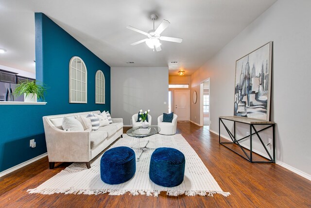 living area featuring baseboards, ceiling fan, visible vents, and wood finished floors