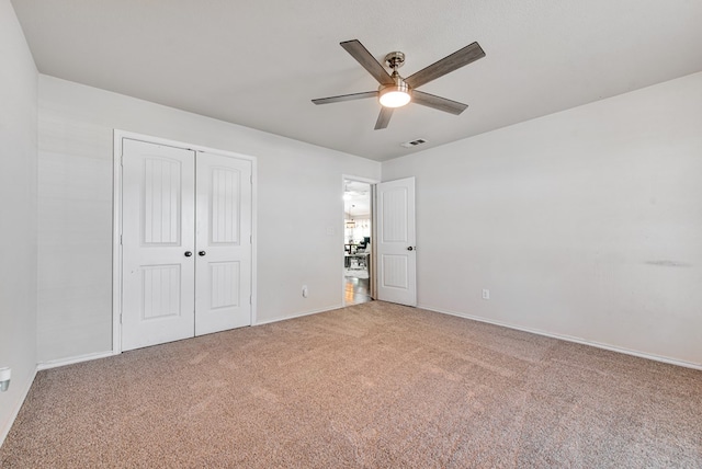 unfurnished bedroom featuring visible vents, carpet floors, a closet, baseboards, and ceiling fan
