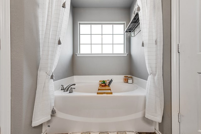bathroom with a textured wall and a garden tub