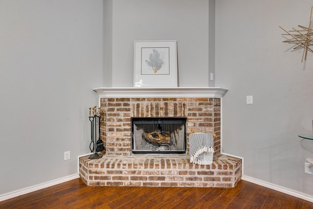 room details featuring baseboards, a brick fireplace, and wood finished floors