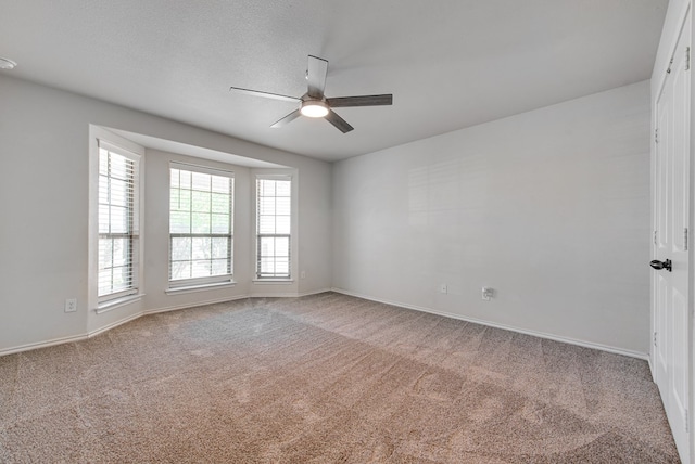 carpeted spare room featuring baseboards and a ceiling fan
