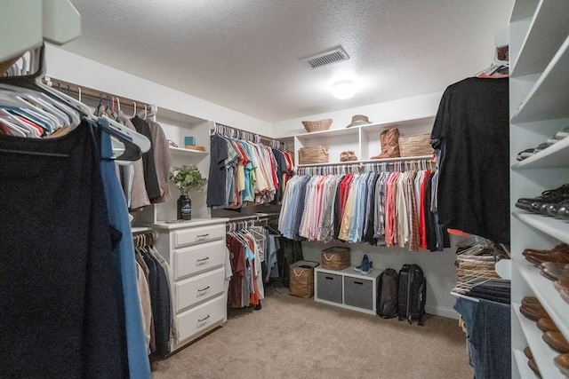 walk in closet featuring visible vents and light colored carpet