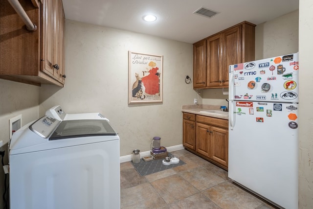 clothes washing area featuring visible vents, baseboards, washer and dryer, cabinet space, and a sink