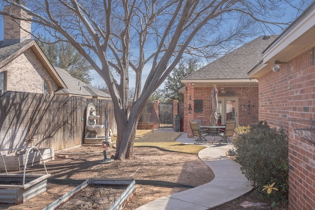 view of yard featuring a patio area, a gate, a vegetable garden, and fence