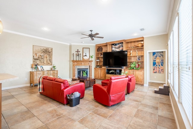 living room with a glass covered fireplace, ceiling fan, baseboards, and ornamental molding