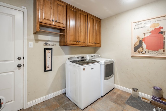 clothes washing area with separate washer and dryer, cabinet space, and baseboards