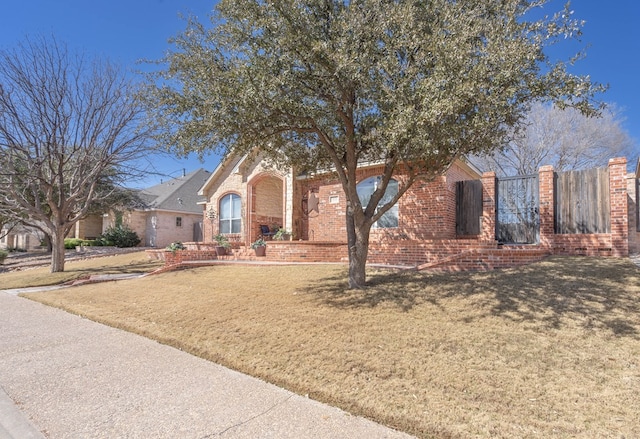 obstructed view of property with a front lawn, fence, and brick siding