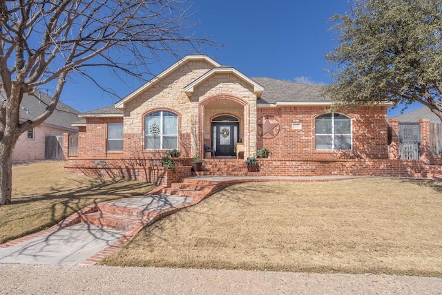 ranch-style house featuring stone siding, brick siding, a front yard, and a shingled roof