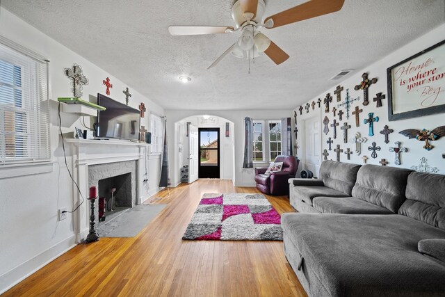 407 Edwards Blvd, Big Spring, TX 79720 - living area with arched walkways, a textured ceiling, wood finished floors, ceiling fan, and a fireplace with flush hearth