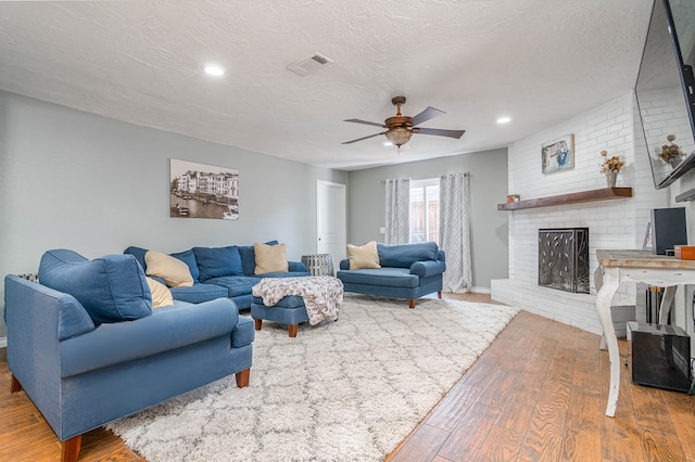 4100 Skyline Dr, Midland, TX 79707 - living room featuring wood-type flooring, a ceiling fan, a textured ceiling, a fireplace, and recessed lighting