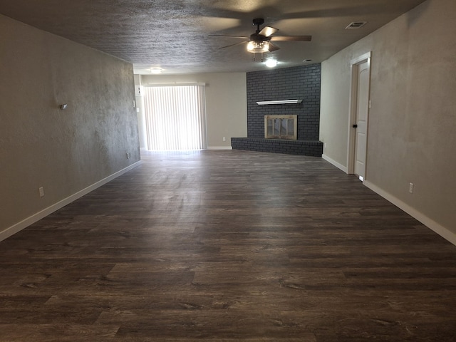 4011 Houston Ave, Snyder, TX 79549 - unfurnished living room featuring dark wood-style flooring, visible vents, a fireplace, and ceiling fan