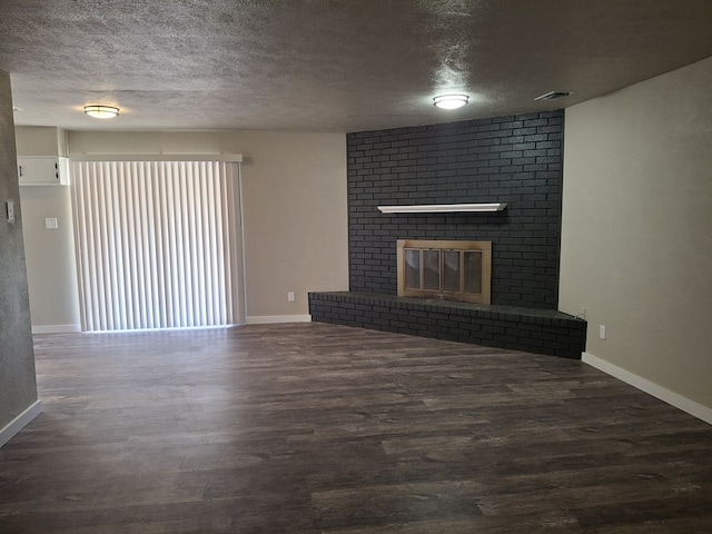 4011 Houston Ave, Snyder, TX 79549 - unfurnished living room featuring a textured ceiling, visible vents, wood finished floors, and a brick fireplace