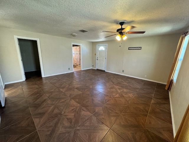empty room with a textured ceiling, ceiling fan, and dark parquet floors