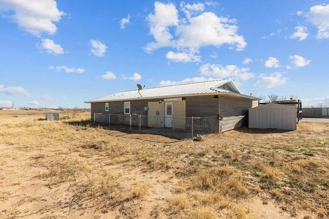 back of house with a storage shed