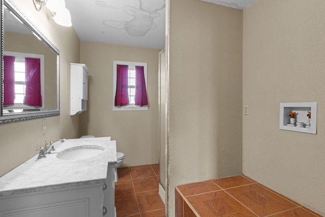 bathroom with vanity, toilet, a healthy amount of sunlight, and tile patterned floors