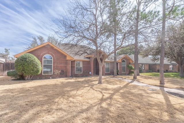 view of front of house with a front yard, fence, and brick siding