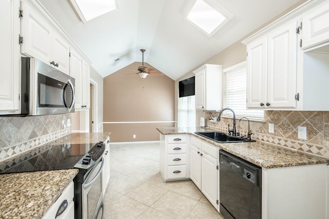 kitchen with ceiling fan, a sink, vaulted ceiling, appliances with stainless steel finishes, and light stone countertops