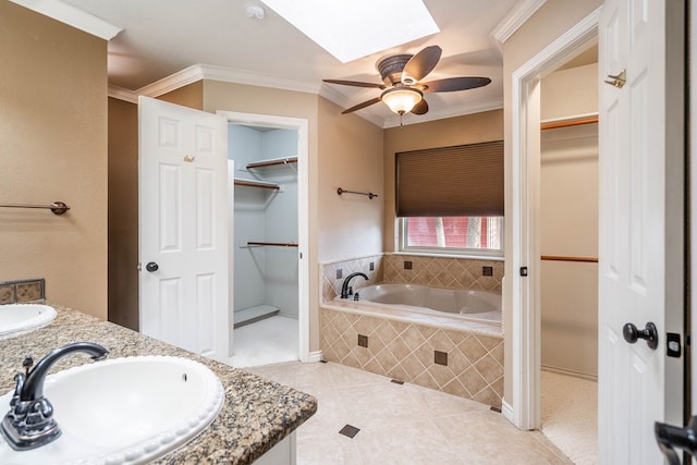 bathroom with a skylight, crown molding, a walk in closet, and a sink