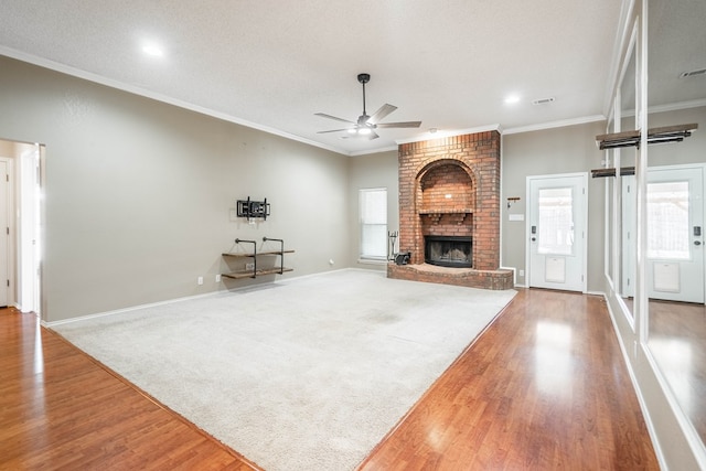 living area featuring a textured ceiling, ornamental molding, a fireplace, and wood finished floors