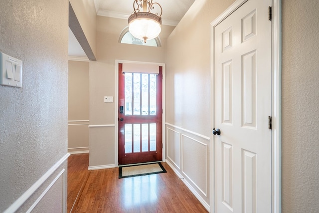 entryway featuring a textured wall, wood finished floors, and crown molding