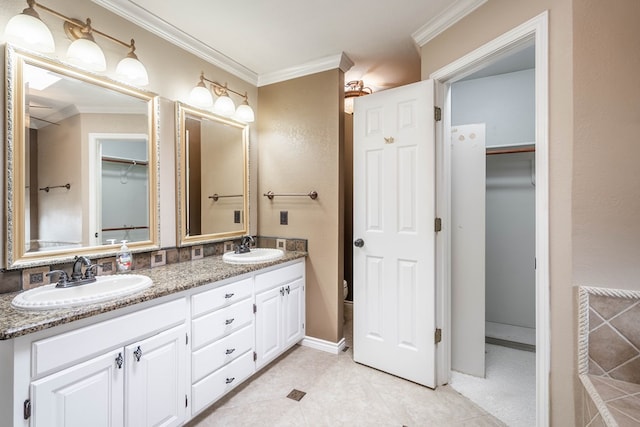 bathroom featuring crown molding, a walk in closet, a sink, and double vanity