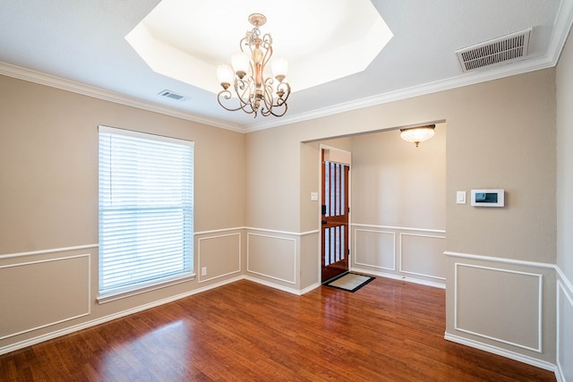 unfurnished room with a chandelier, a tray ceiling, wood finished floors, and visible vents