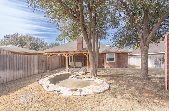 rear view of house with a chimney, brick siding, a patio, and a fenced backyard