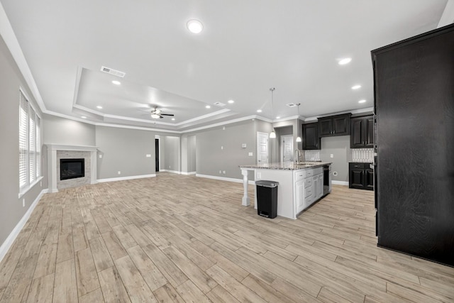 1803 Overshine Ln, Midland, TX 79705 - unfurnished living room with a ceiling fan, a tray ceiling, light wood-type flooring, a glass covered fireplace, and recessed lighting