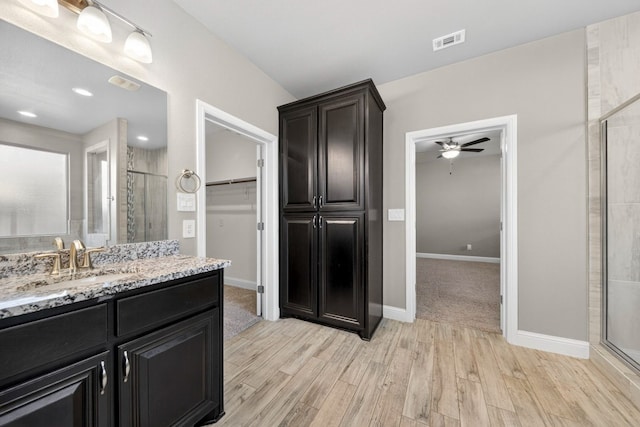 1803 Overshine Ln, Midland, TX 79705 - bathroom featuring wood finished floors, a shower stall, vanity, a spacious closet, and a ceiling fan