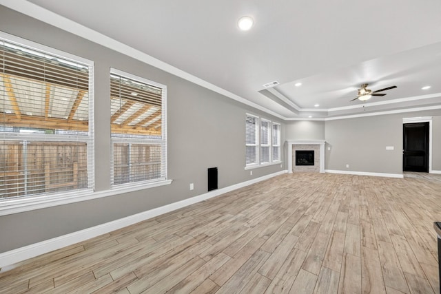 1803 Overshine Ln, Midland, TX 79705 - unfurnished living room featuring light wood-style flooring, a tray ceiling, a ceiling fan, recessed lighting, and a fireplace