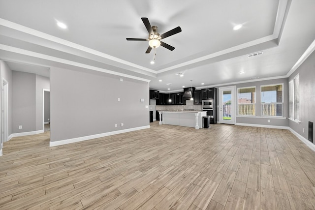 1803 Overshine Ln, Midland, TX 79705 - unfurnished living room with a raised ceiling, ceiling fan, light wood finished floors, recessed lighting, and ornamental molding