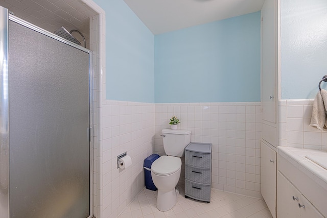 bathroom featuring a wainscoted wall, tile walls, toilet, and a shower stall