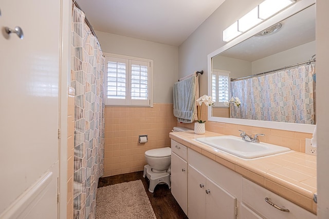 bathroom with vanity, toilet, a wainscoted wall, tile walls, and wood finished floors