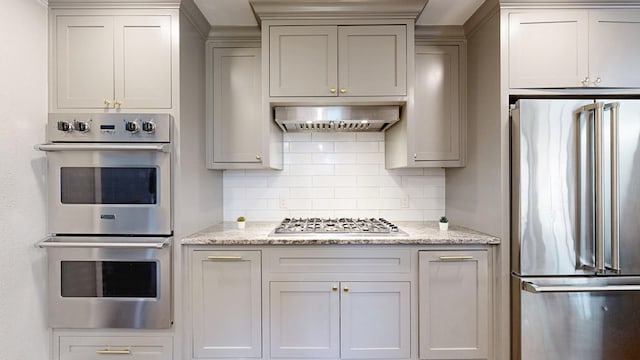 kitchen featuring backsplash, stainless steel appliances, light stone counters, and gray cabinets