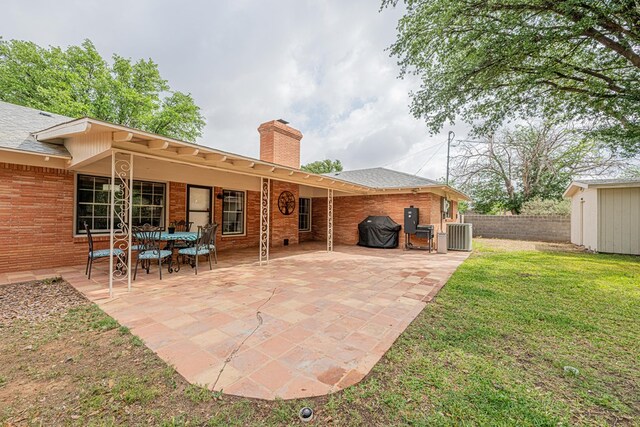 rear view of property with fence, a patio, a chimney, and brick siding