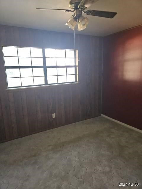 unfurnished room featuring ceiling fan and wooden walls