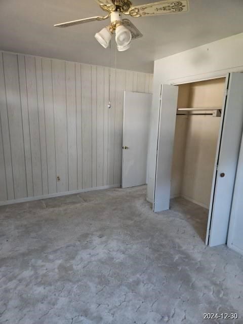 unfurnished bedroom with ceiling fan and wooden walls